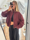 Trendy wijnrode damesjas met korte, ruime pasvorm, opstaande kraag en rits, stijlvolle oversized outerwear en casual chic, weinrote Jacke en modieuze Damenmode van ByLies.