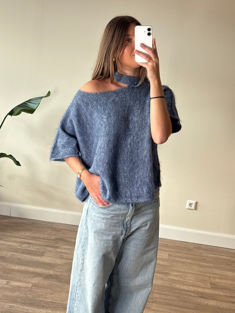 Mooie blauwe oversized damestrui met een asymmetrische off shoulder halslijn, korte wijde mouwen en een heerlijk zachte fluffy uitstraling. Trendy gebreide trui in jeansblauw, een stijlvolle winter must-have uit de collectie van By Lies.