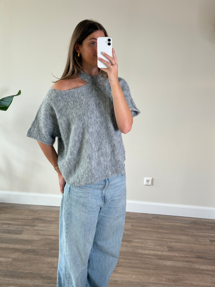 Trendy lichtgrijze oversized trui voor dames met een elegante blote schouder en korte mouwen. Zachte fluffy off shoulder damestrui met asymmetrische halslijn, een mooie gebreide trui voor de herfst en winter van By Lies.